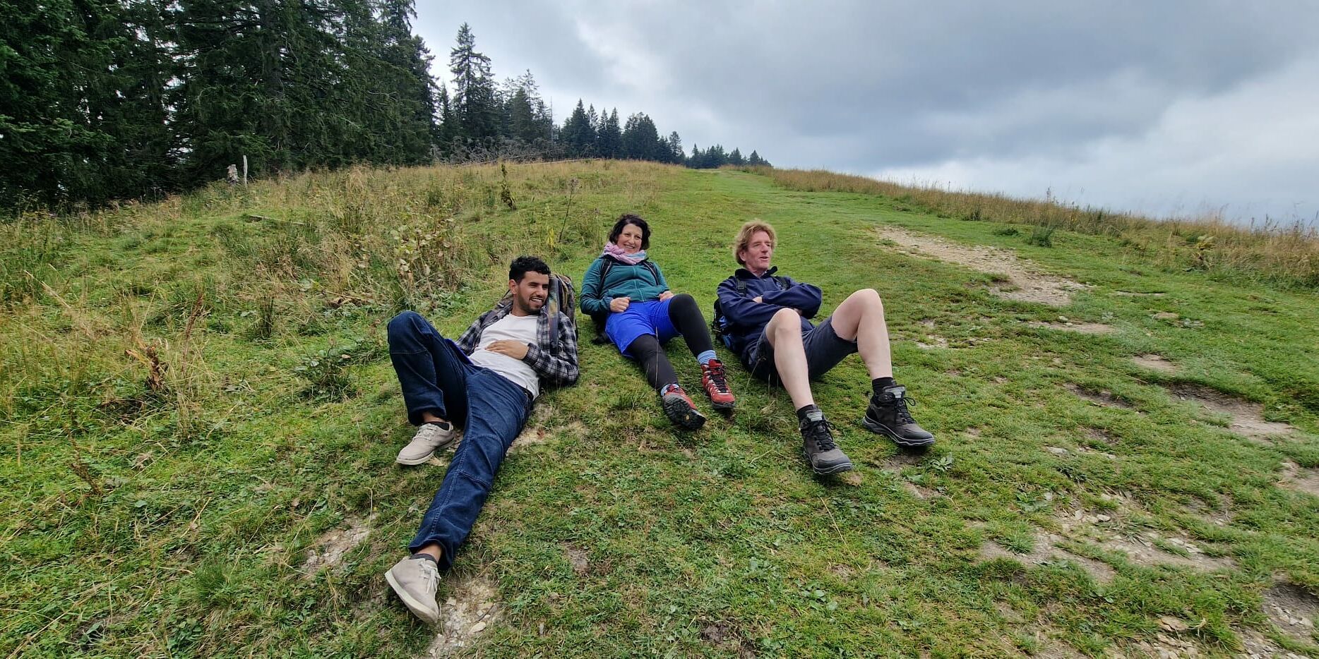 Hier liegen drei Personen auf einer Wiese.