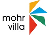Hier ist das Logo der Mohr-Villa Freimann zu sehen. Es zeigt ein buntes Windmühl-Symbol, rechts daneben das Wort "mohr villa"